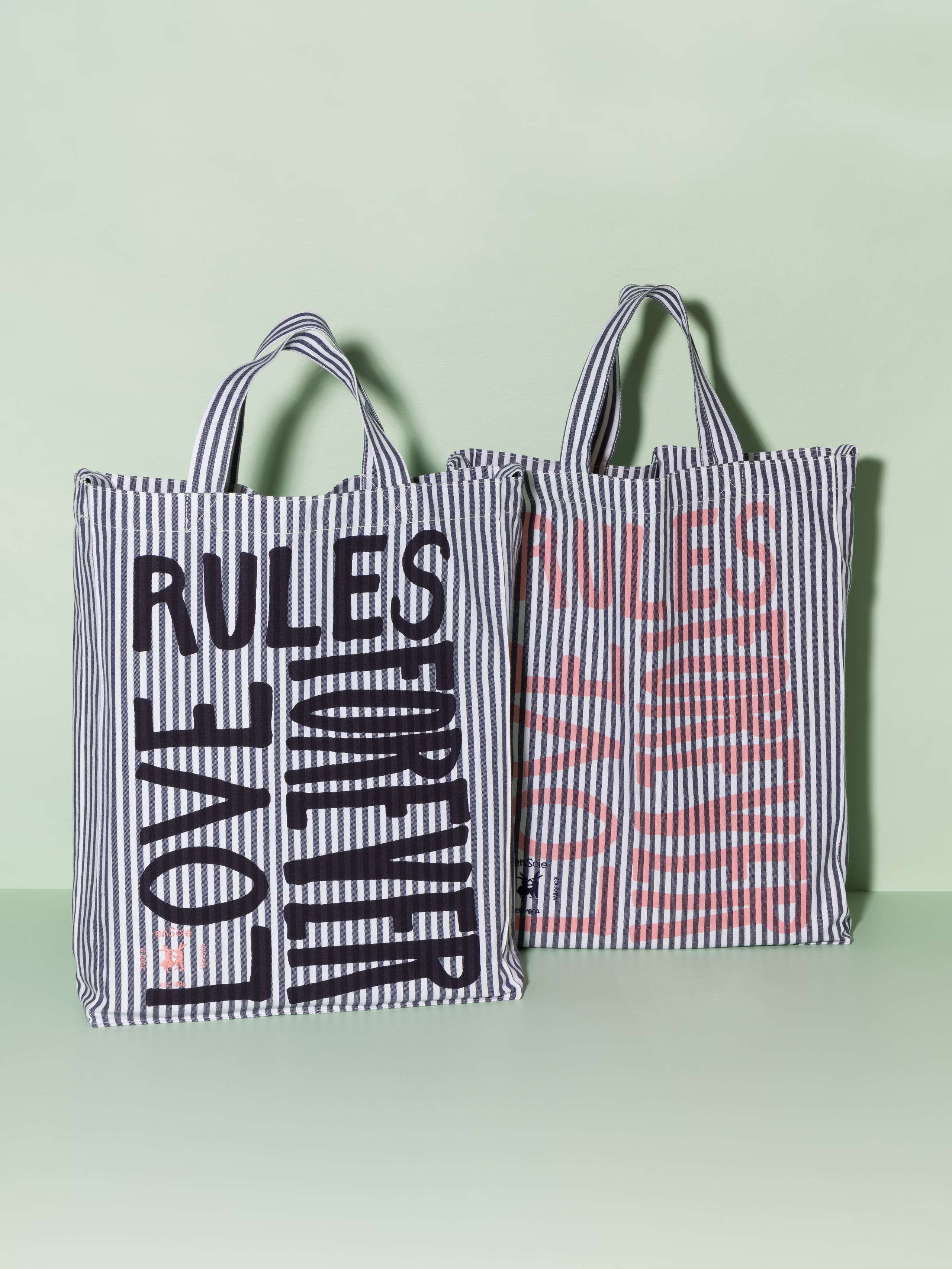 Two cotton tote bags with a navy stripe pattern and a navy and rose print that says "Love rules forever"