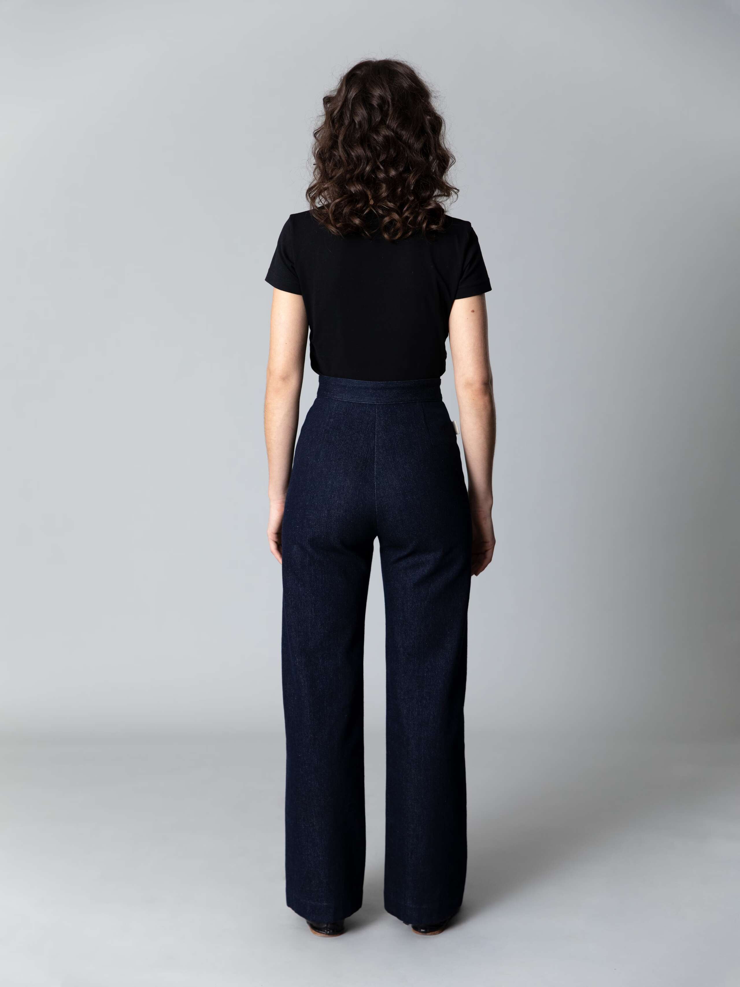 Model wears beautiful wide leg and high waist denim trousers and a black cotton shirt