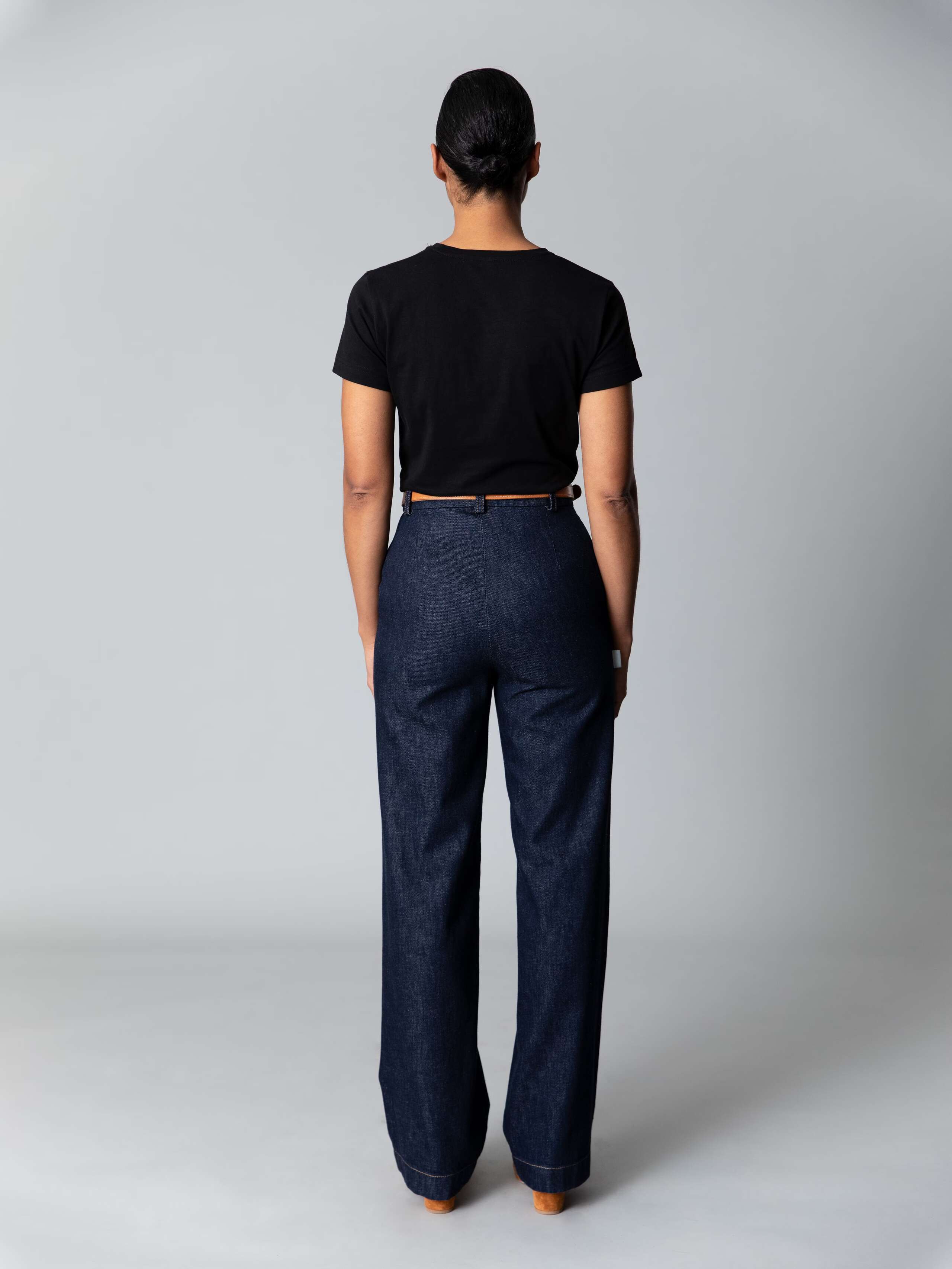 Model is weraing a cotton denim hsgh waist and straight leg jeans in a classy indigo colour combined with a white shirt and black ballerina flats 