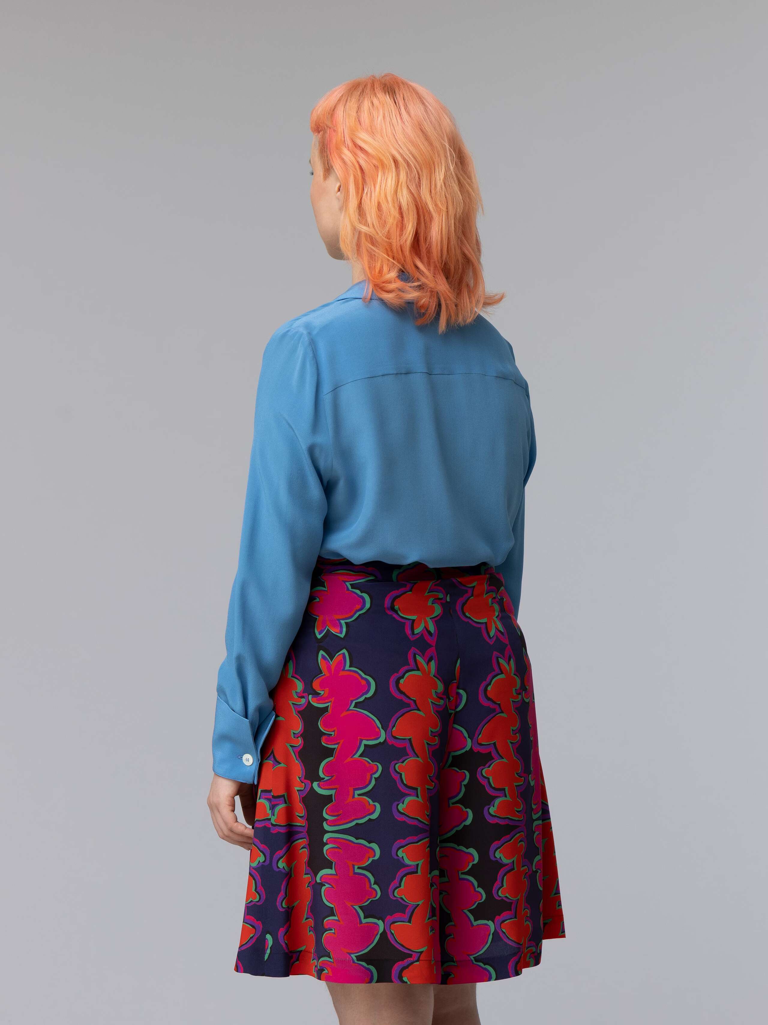 Model wears a blue silk blouse combined with wide summery shorts