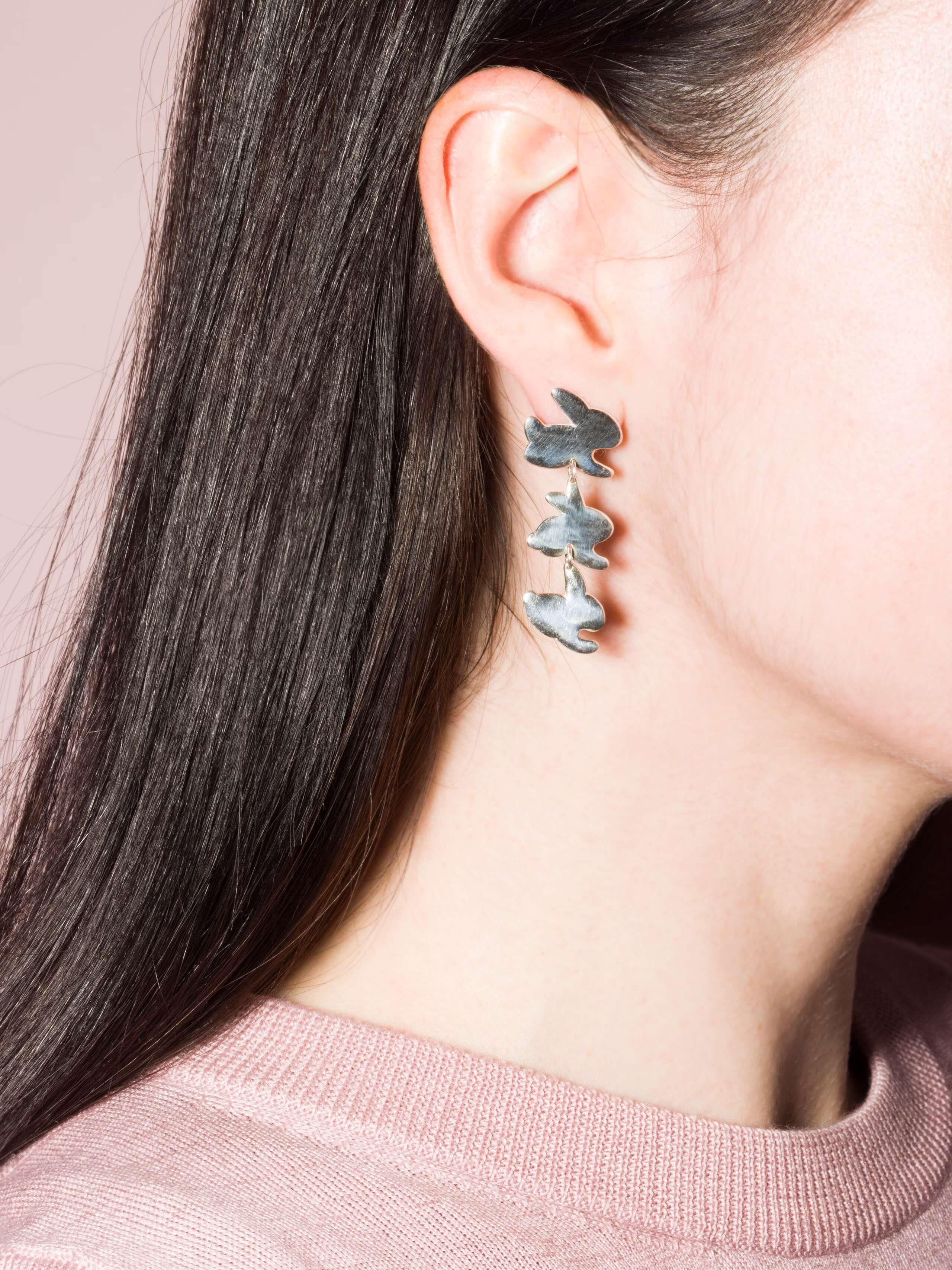 Model wears silver ear studs with three cute rabbits