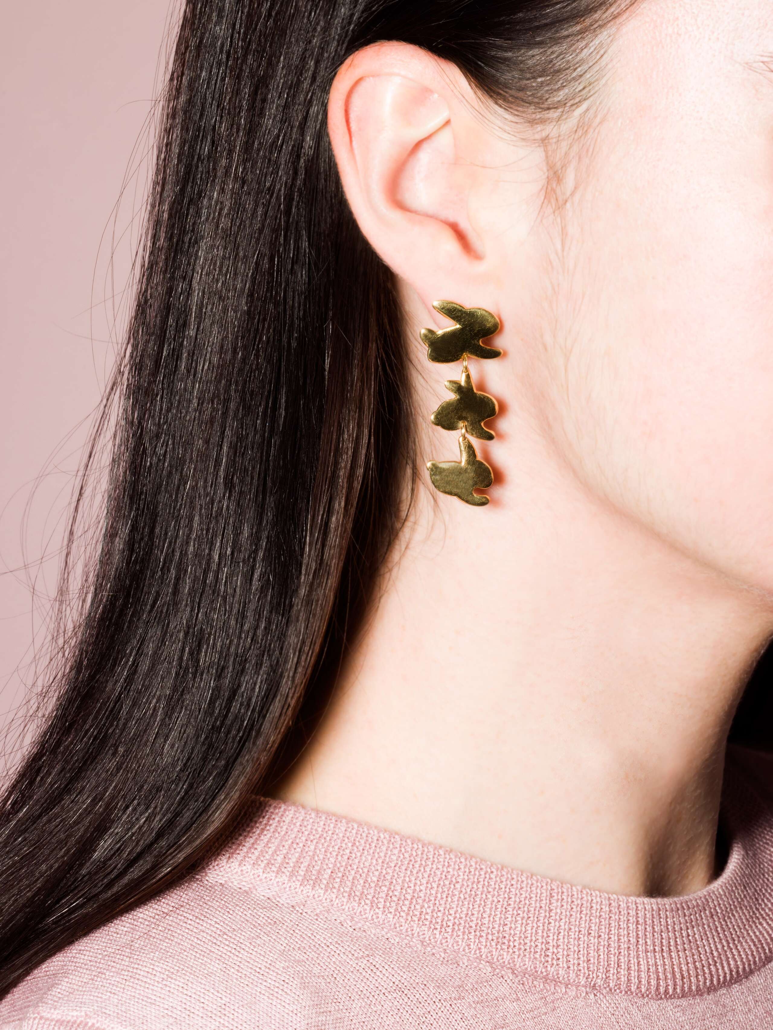Model wears brass ear studs with three cute rabbits