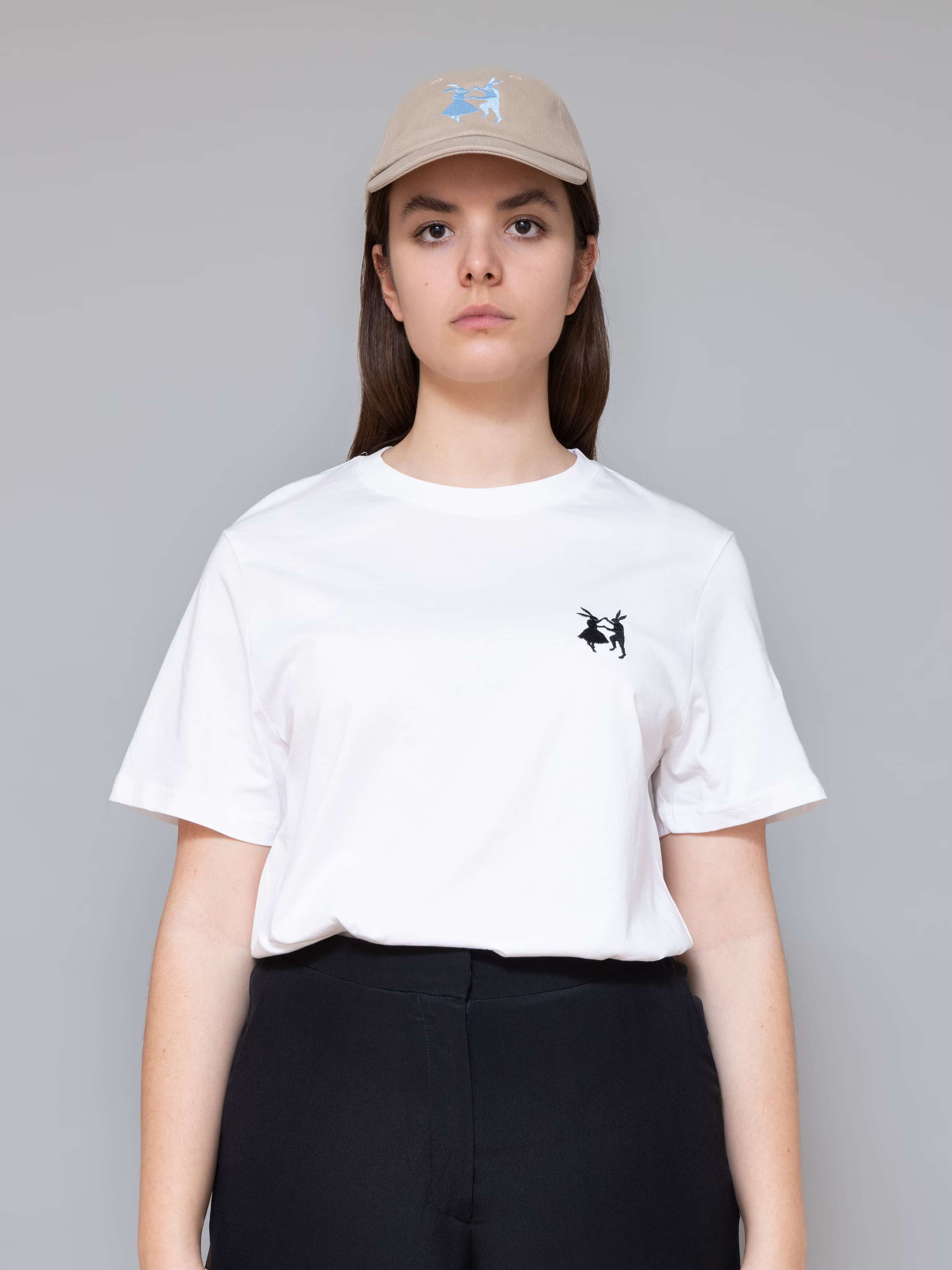 Picture of a female model wearing a beige base cap with light blue rabbit embroidery