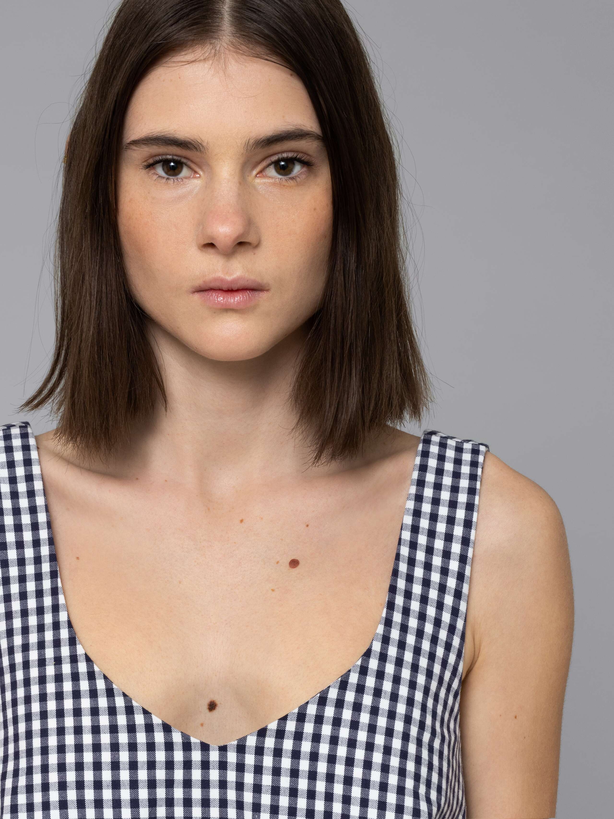 Female model is wearing an airy cotton dress featuring a navy vichy check pattern