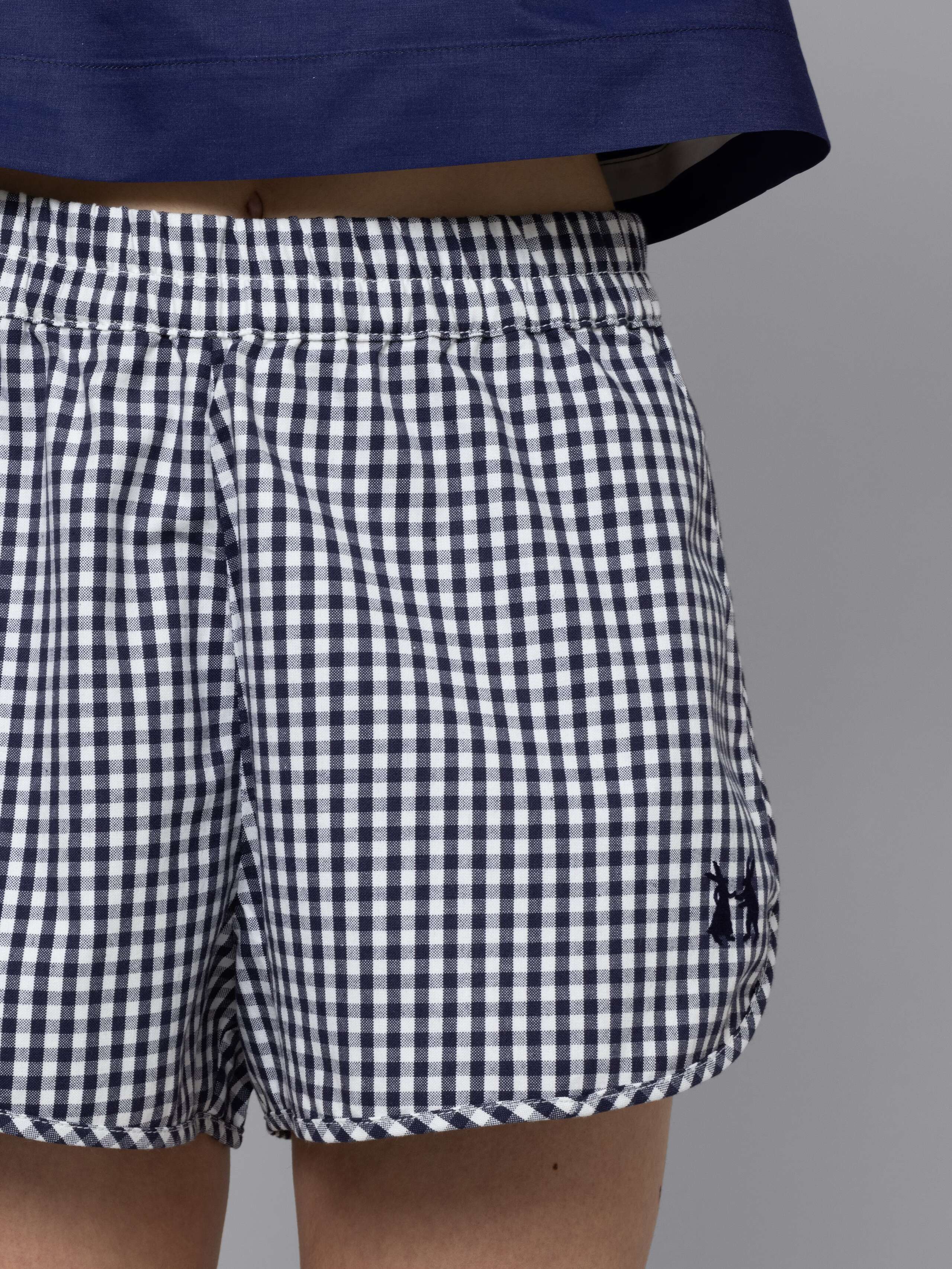 Female model is wearing a sporty cotton short featuring a navy vichy check pattern