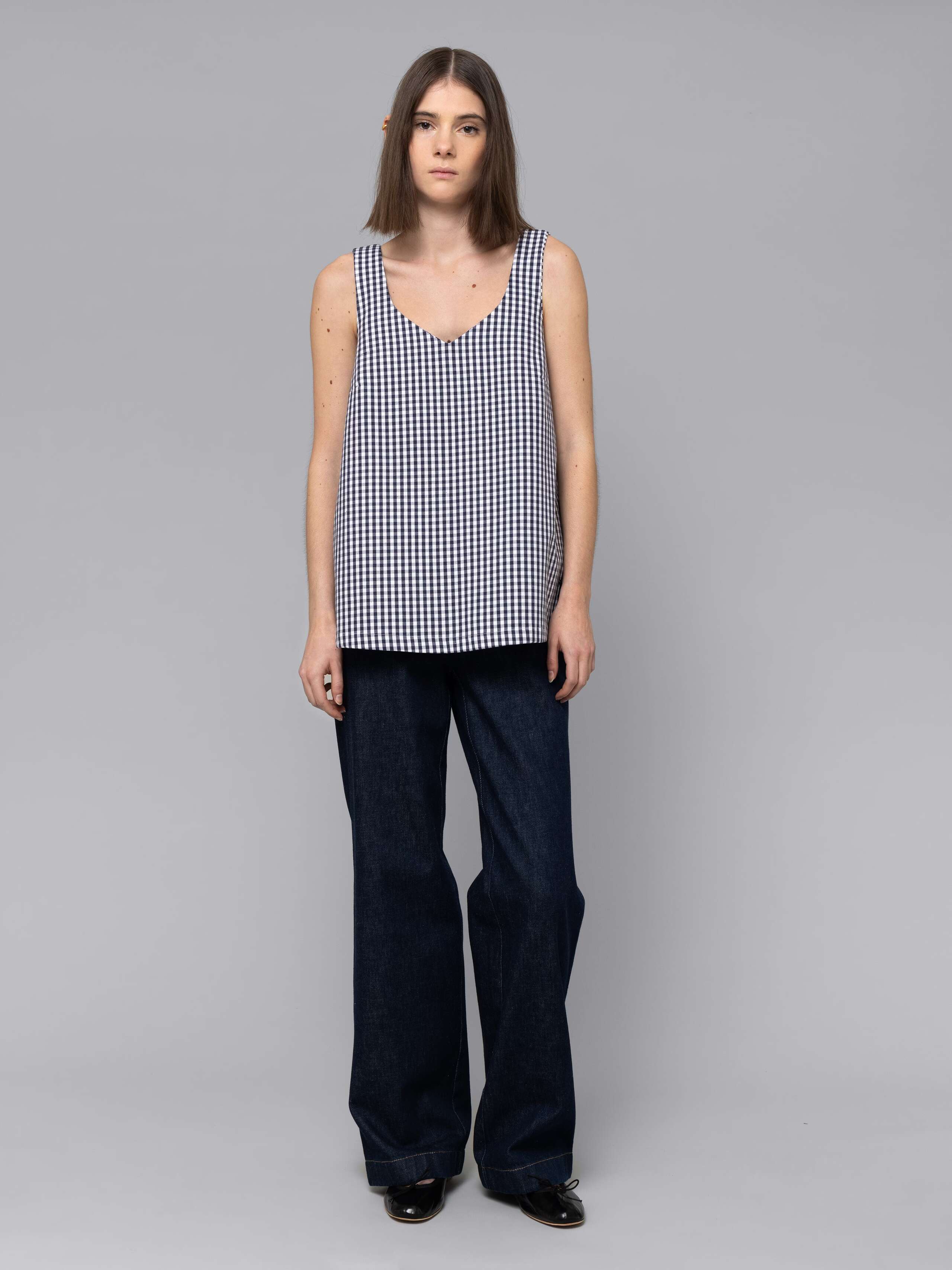 Female model is wearing a an airy long top featuring a beautiful navy vichy check pattern