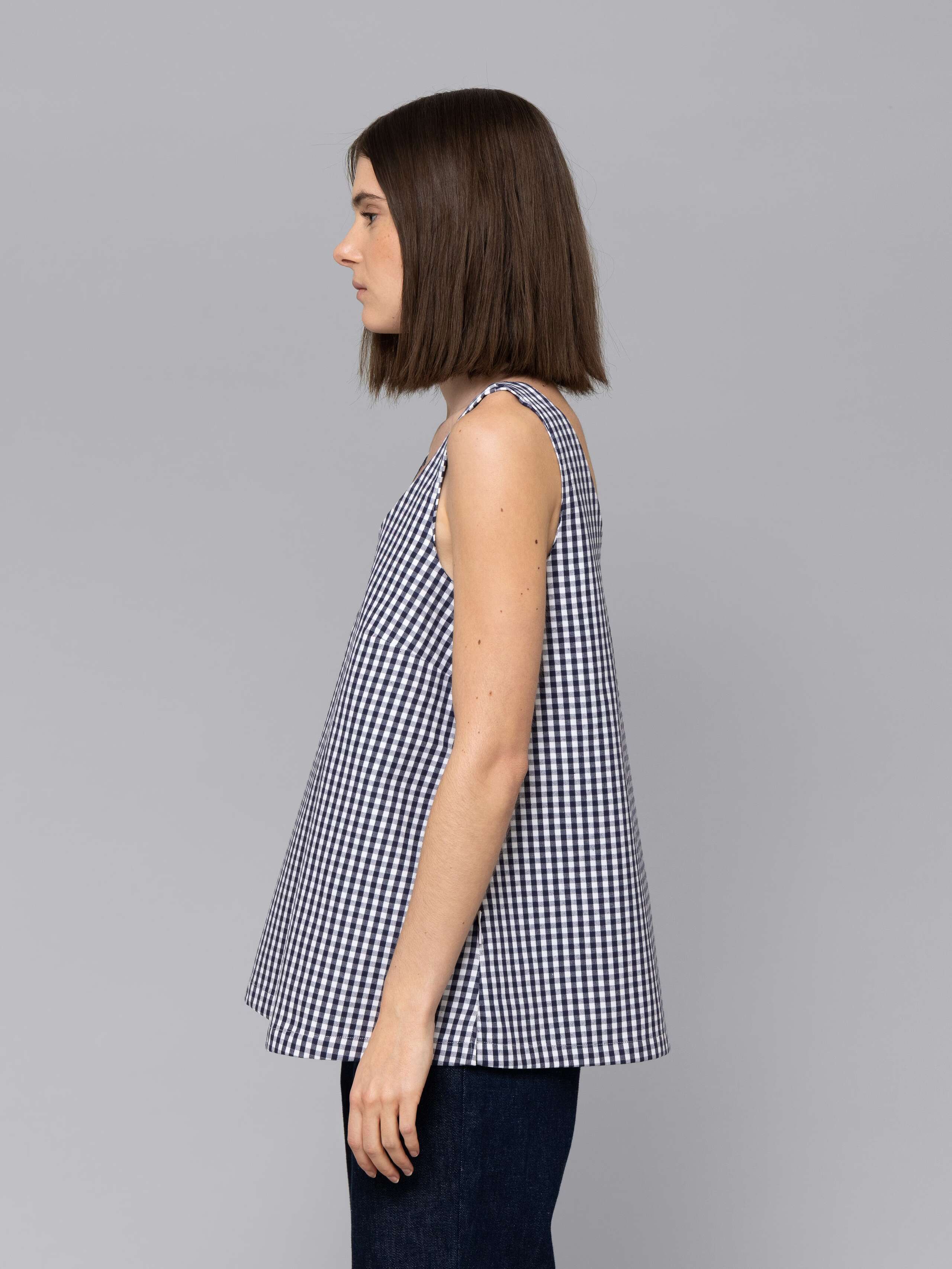 Female model is wearing a an airy long top featuring a beautiful navy vichy check pattern