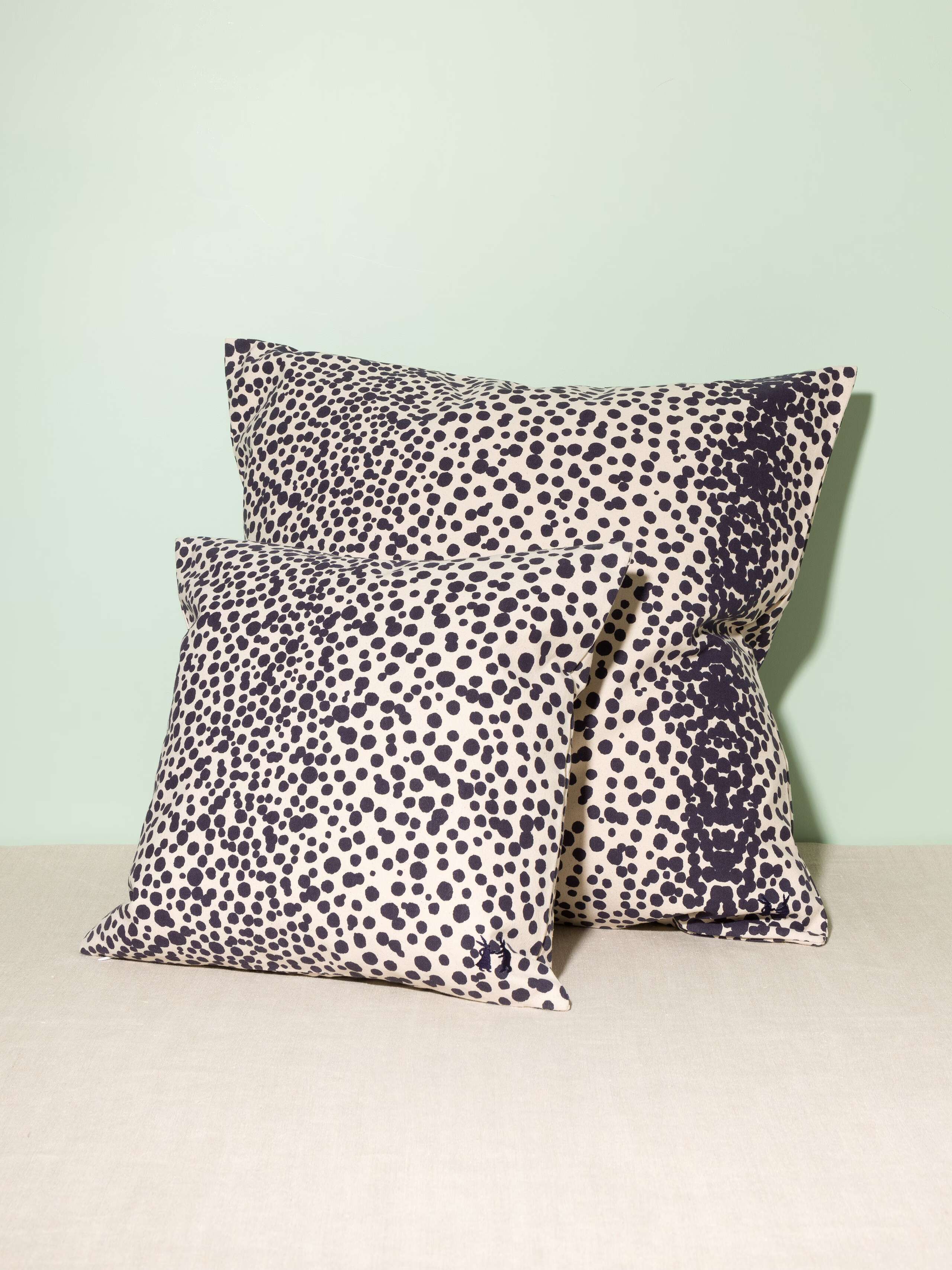 Picture of two pillow covers made from cotton canvas featuring navy blue dots