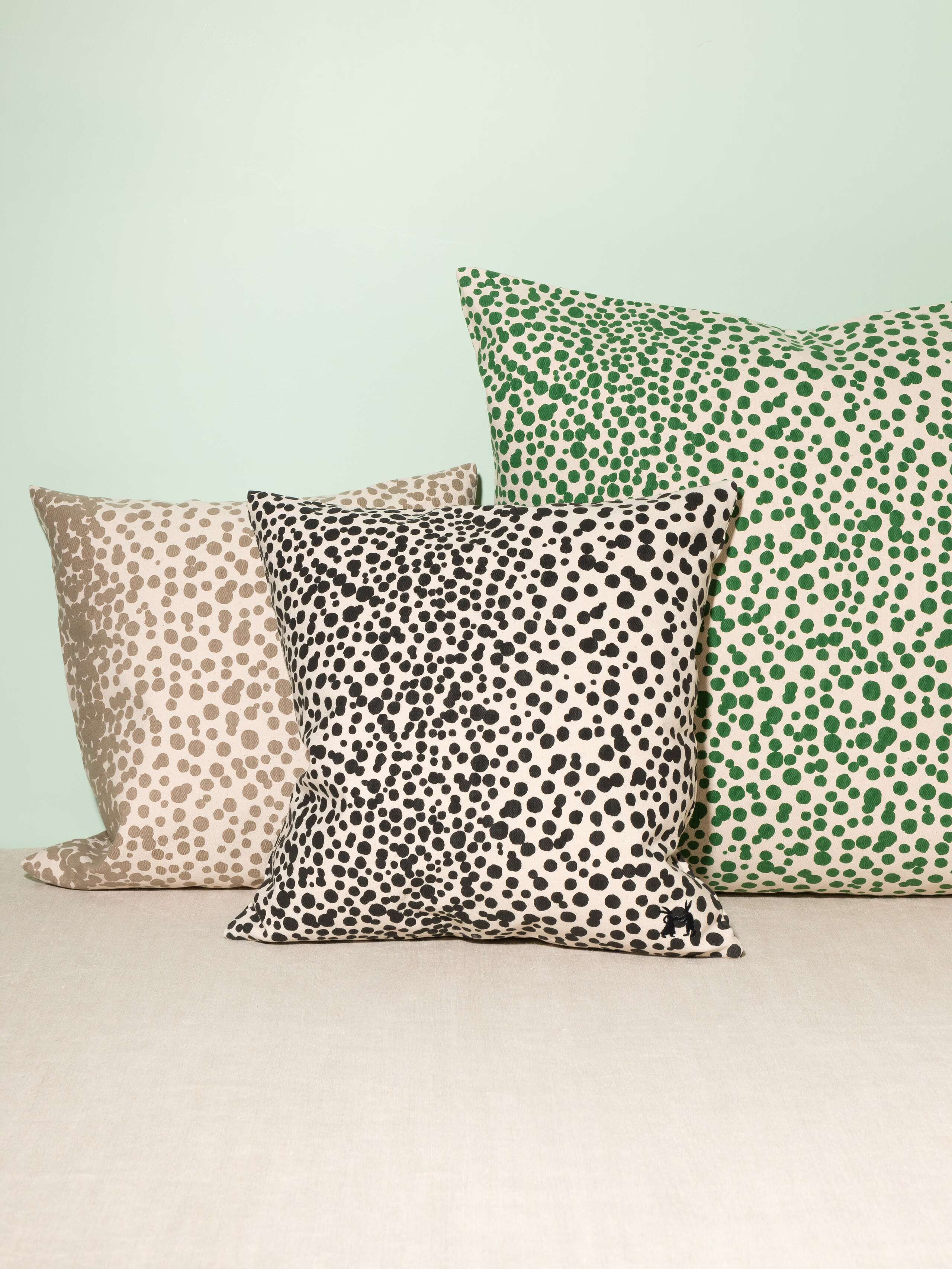 Picture of three pillow covers made of cotton canvas featuring green, pink and beige dots