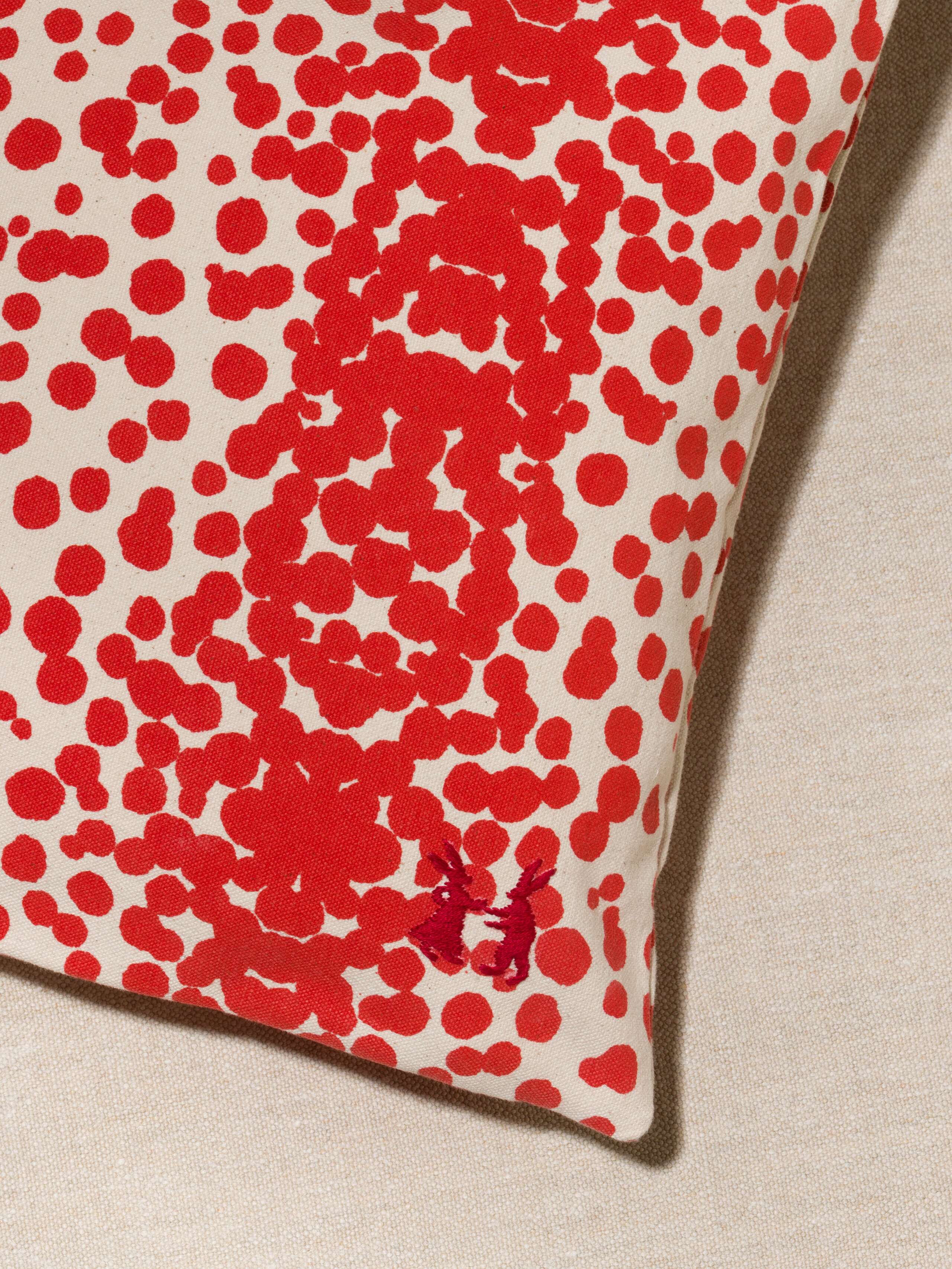 Picture of a detail of a pillow cover made from cotton canvas featuring red dots