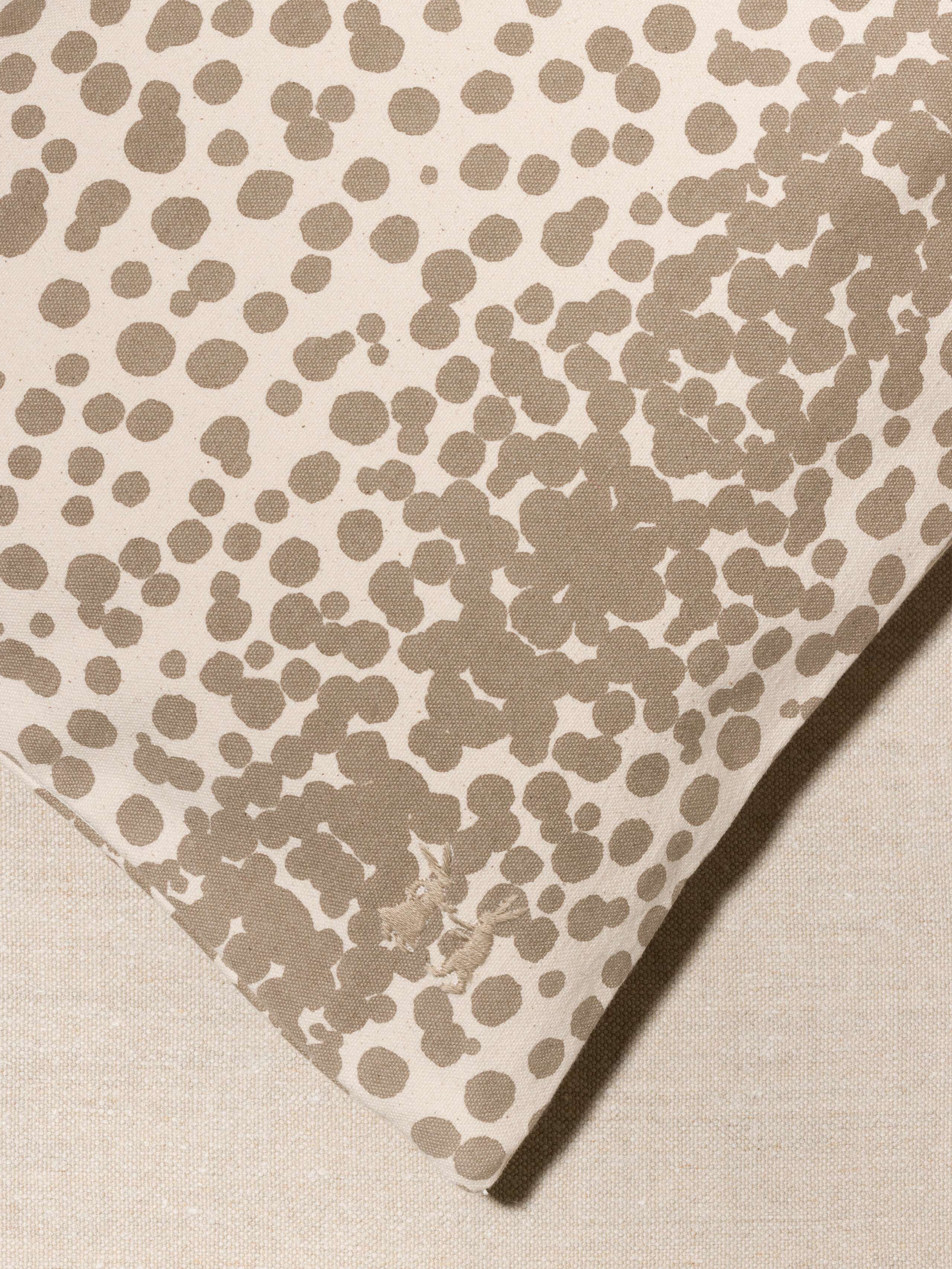 Picture of a detail of a pillow cover made from cotton canvas featuring beige dots