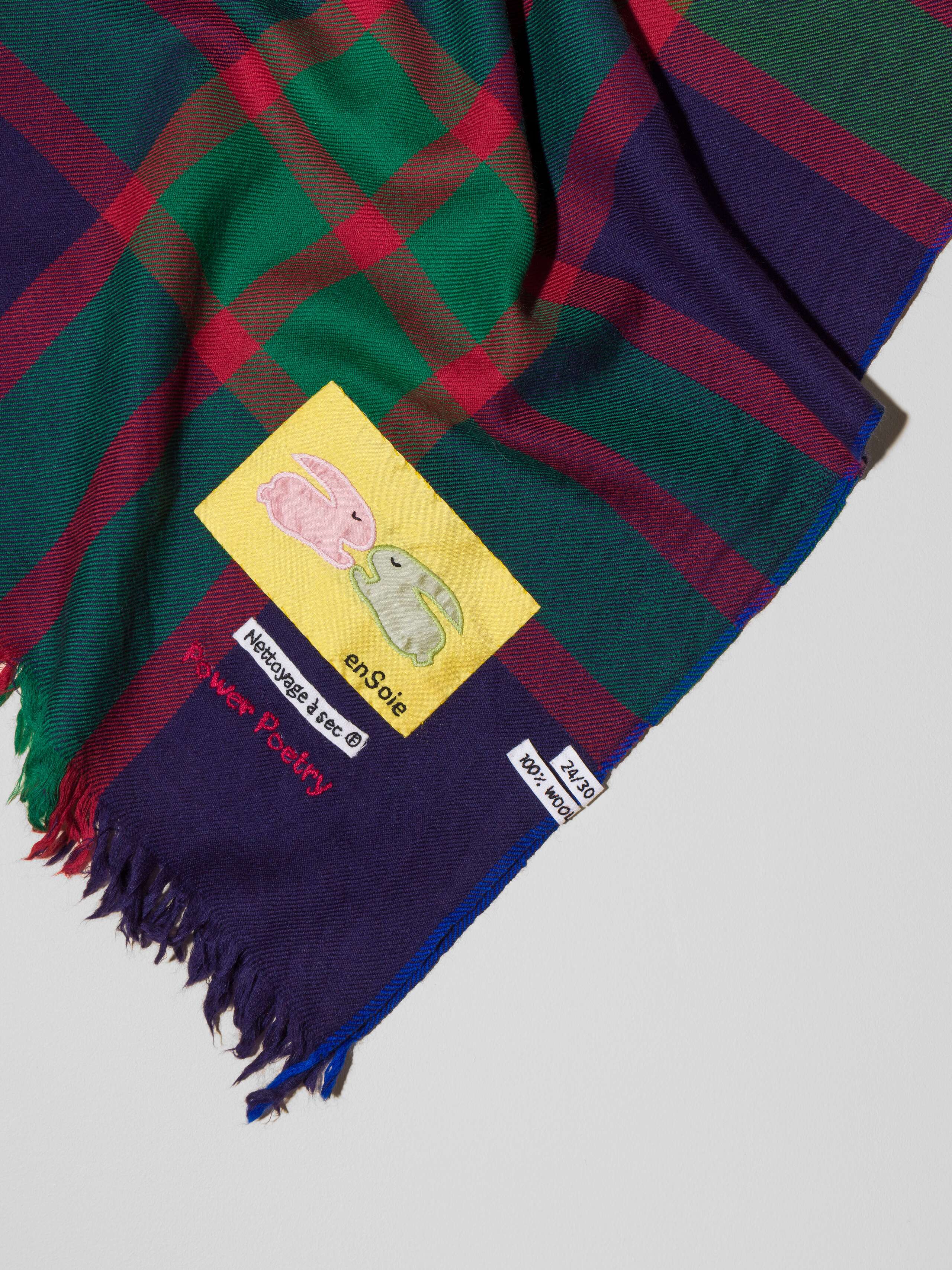Picture of a wool scarf in a dark navy tone featuring a check pattern in green and red shades