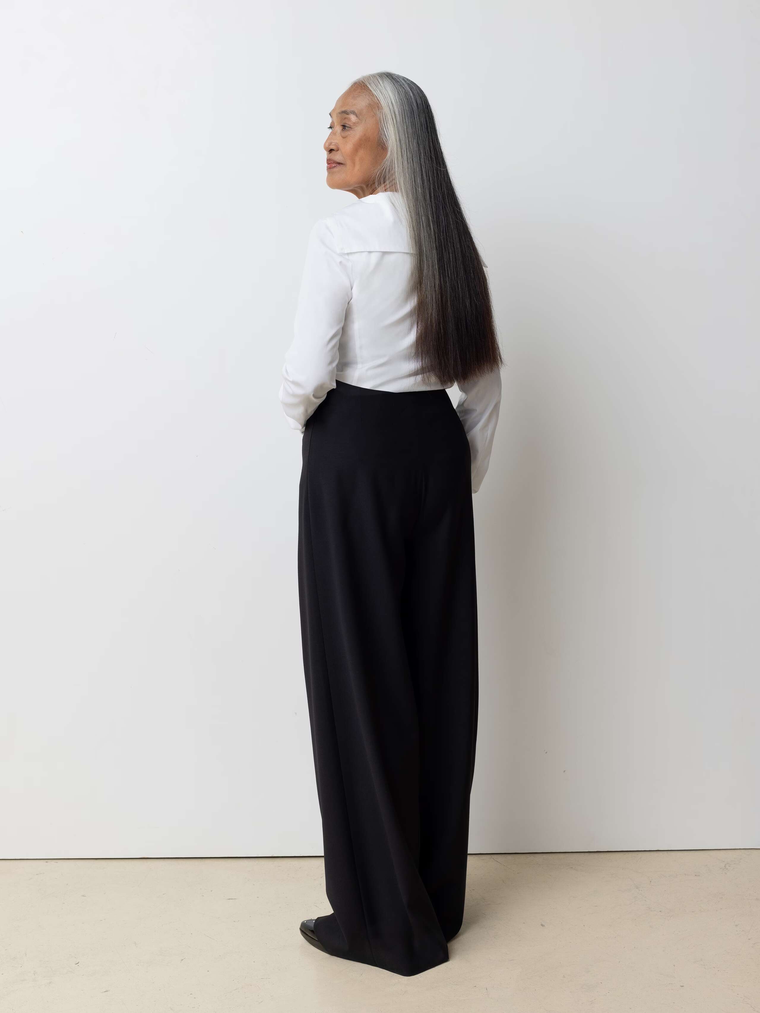 Picture of a female model wearing a whit cotton short in combination with black wool trousers