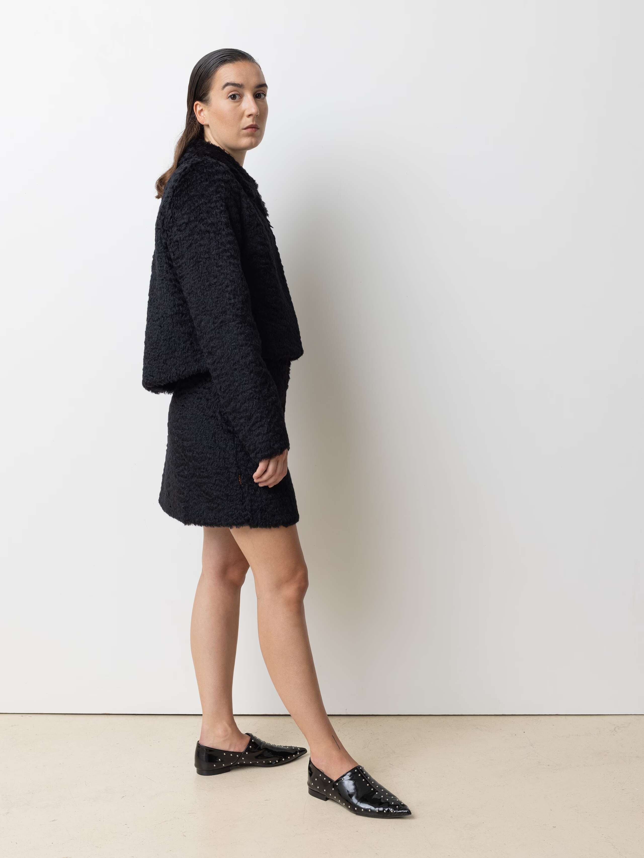 Picture of a female model wearing a combination of a black mohair wool jacket and a short skirt