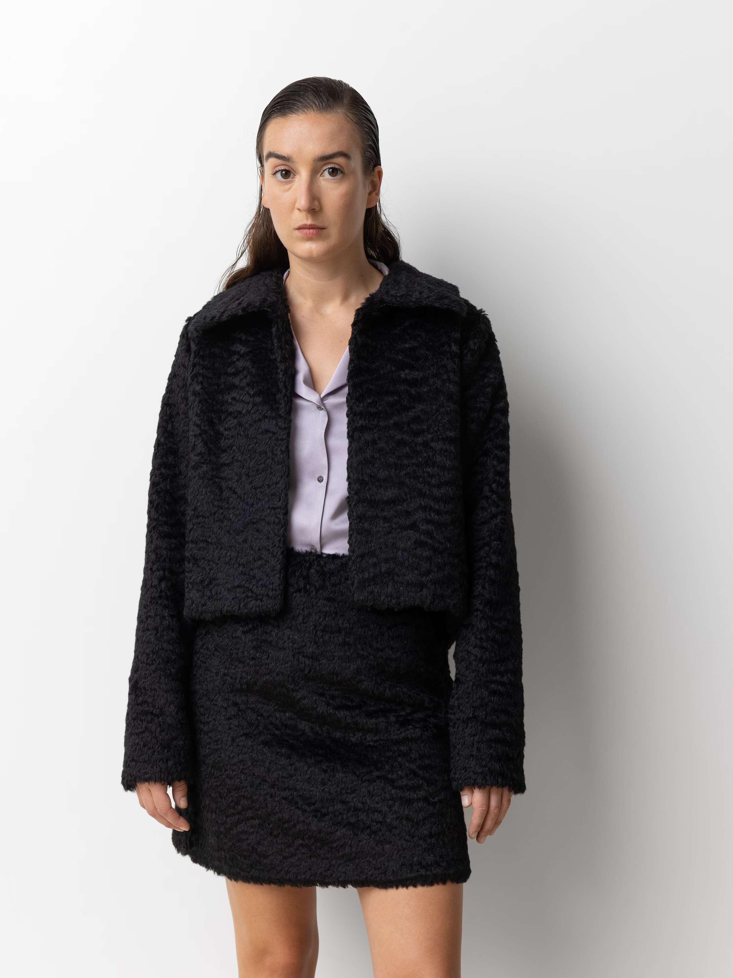 Picture of a female model wearing a combination of a black mohair wool jacket and a short skirt