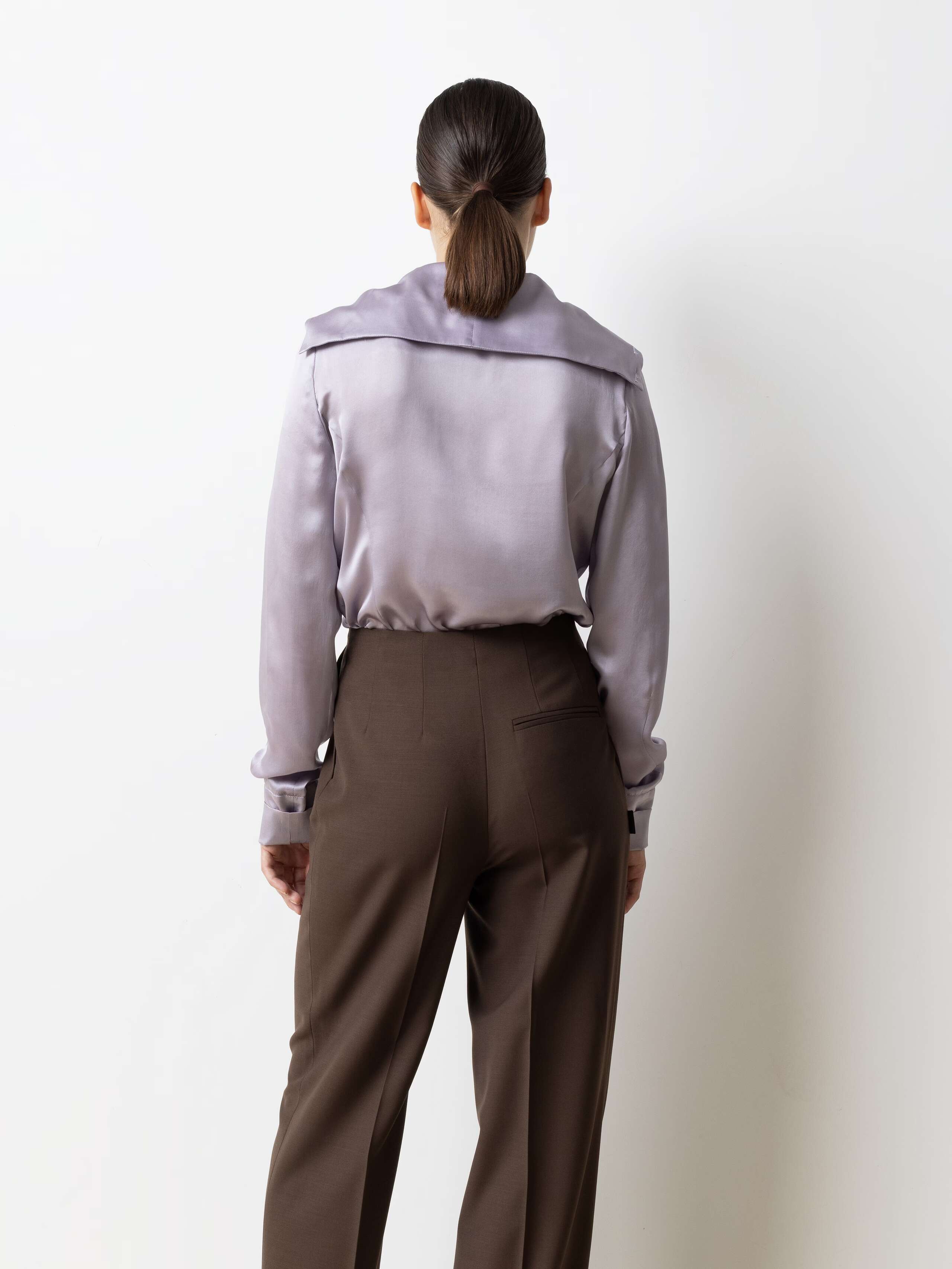 Picture of a model wearing a lavender coloured silk blouse in combination with brown cool wool pant