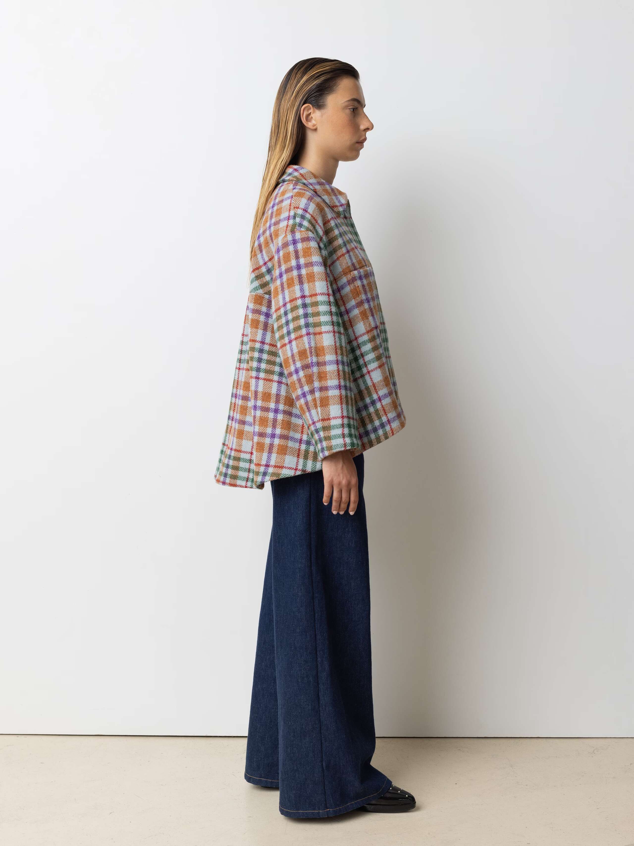 Picture of a female model wearing a wide colourful wool jacket in combination with a wide leg jeans