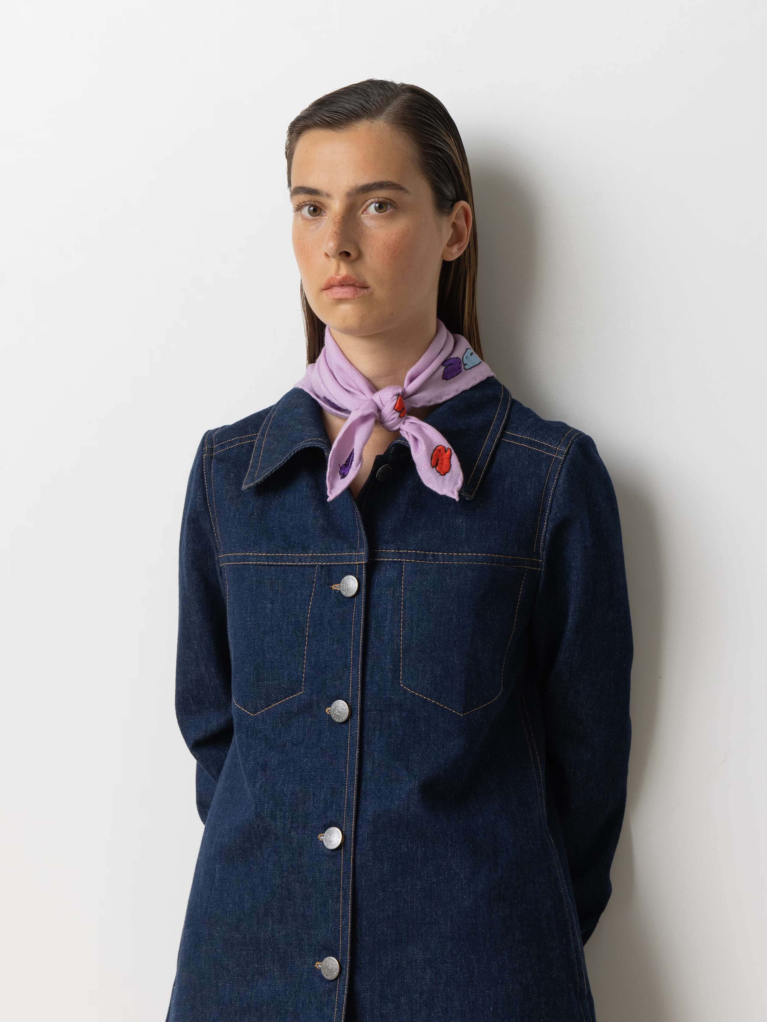 Picture of a female model wearing a denim dress in combination with a small wool foulard