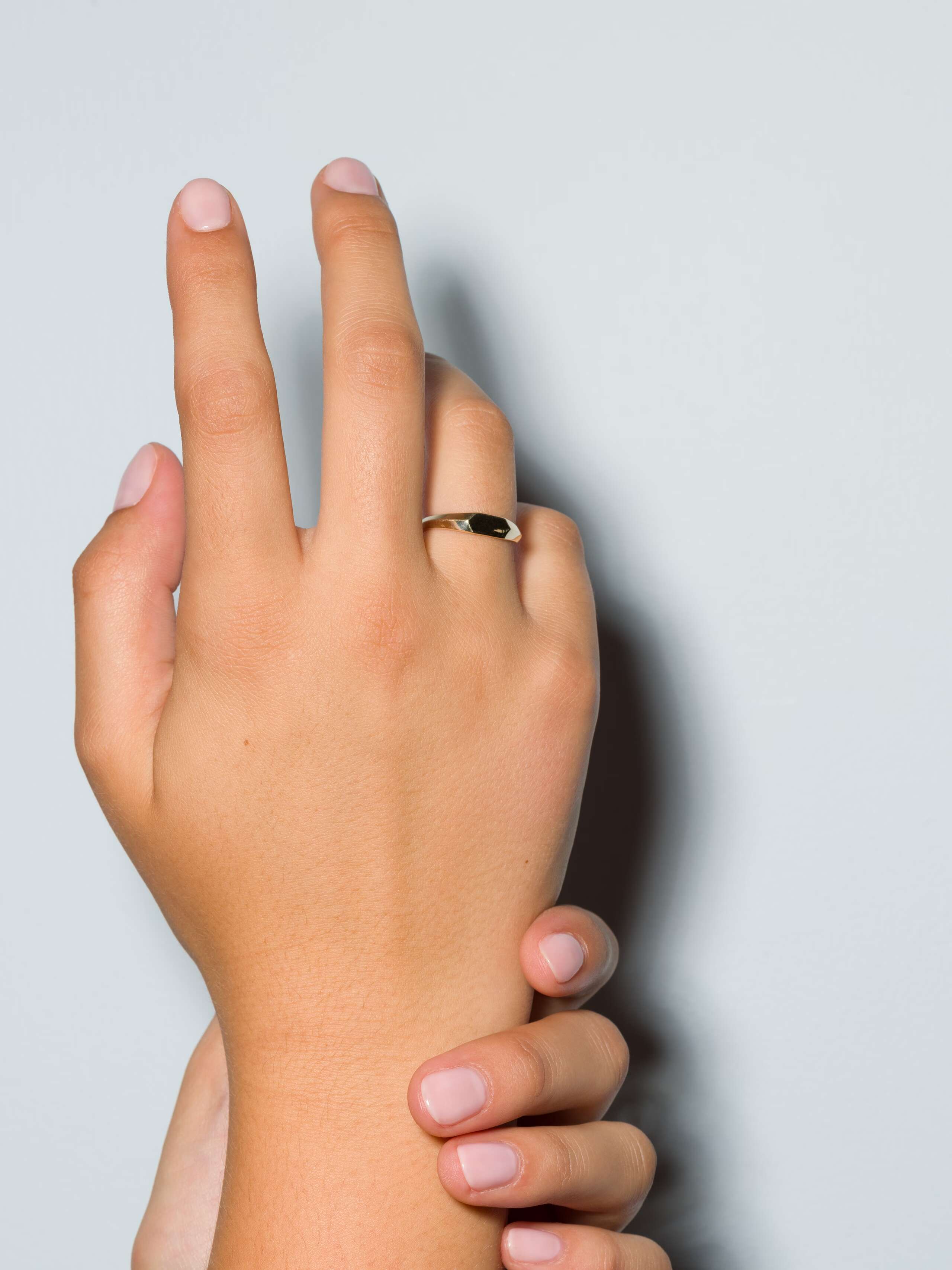 Small 9 karat gold signet ring called Ida on a set of hands