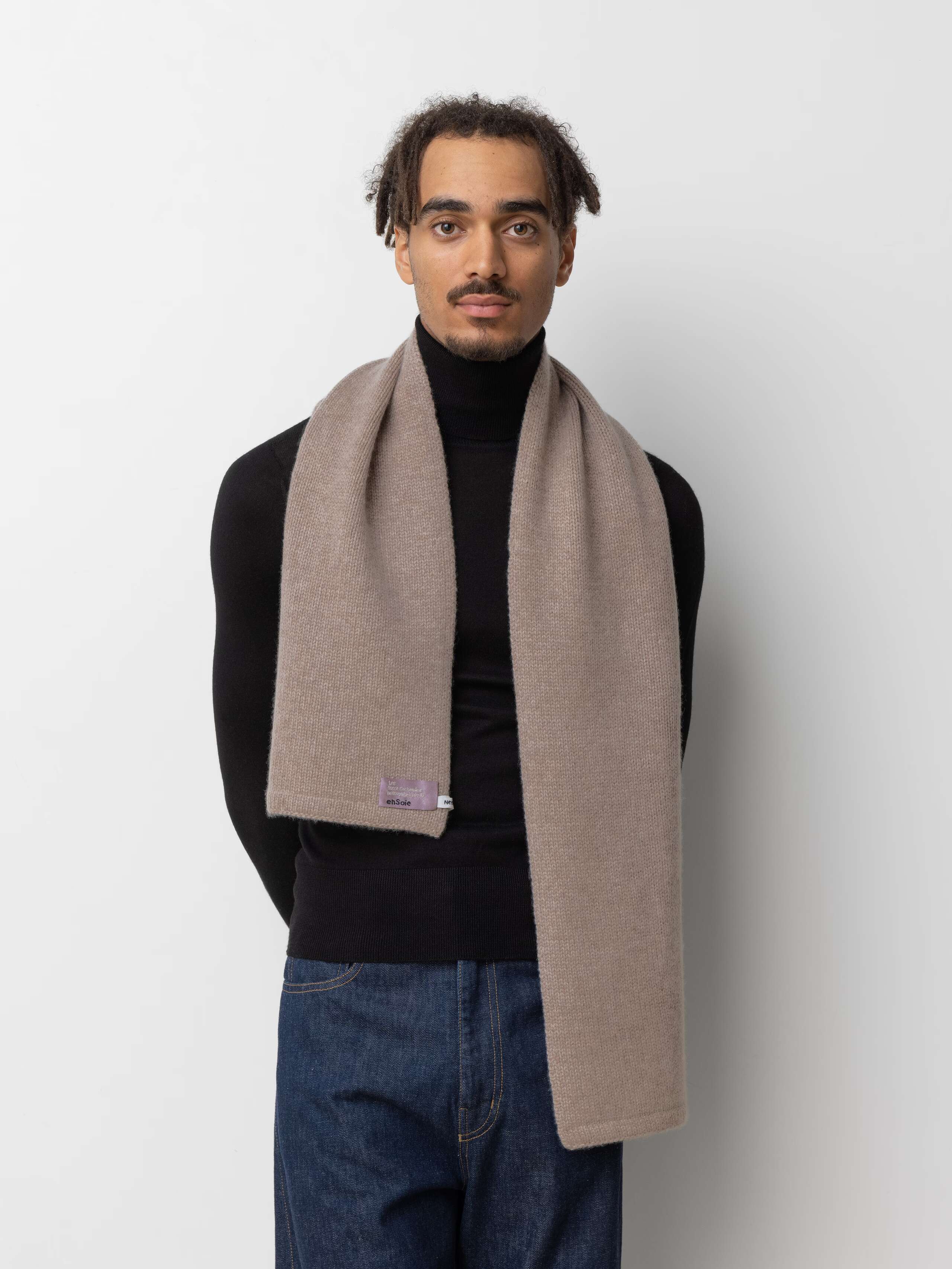 Picture of a male model wearing a black turtleneck in combination with a beige cashmere scarf