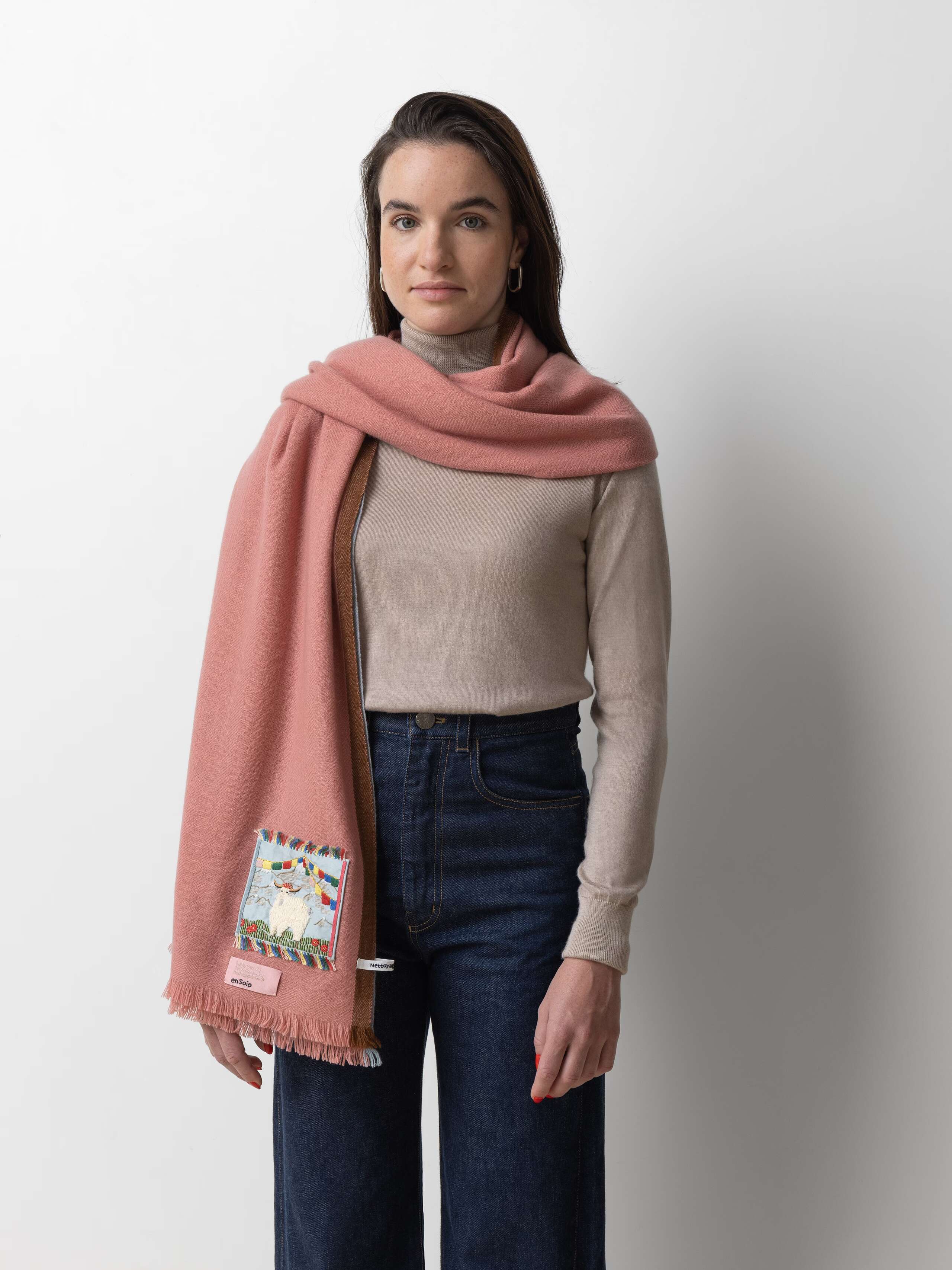 Picture of a female model wearing jeans and a beige turtleneck in combination with a rose cashmere stole