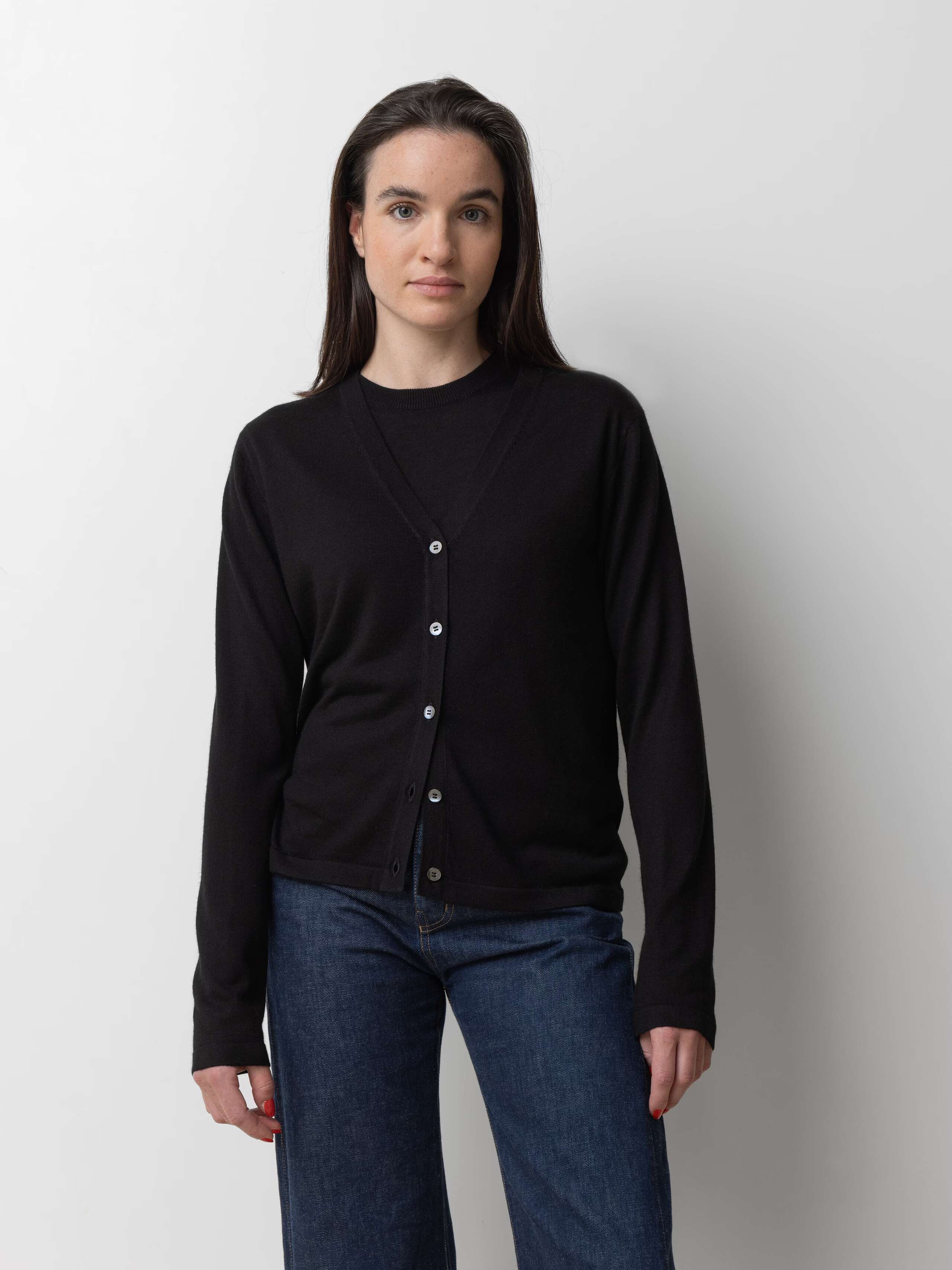 Picture of a female model wearing a black cashmere shirt in combination with a black cashmere cardigan