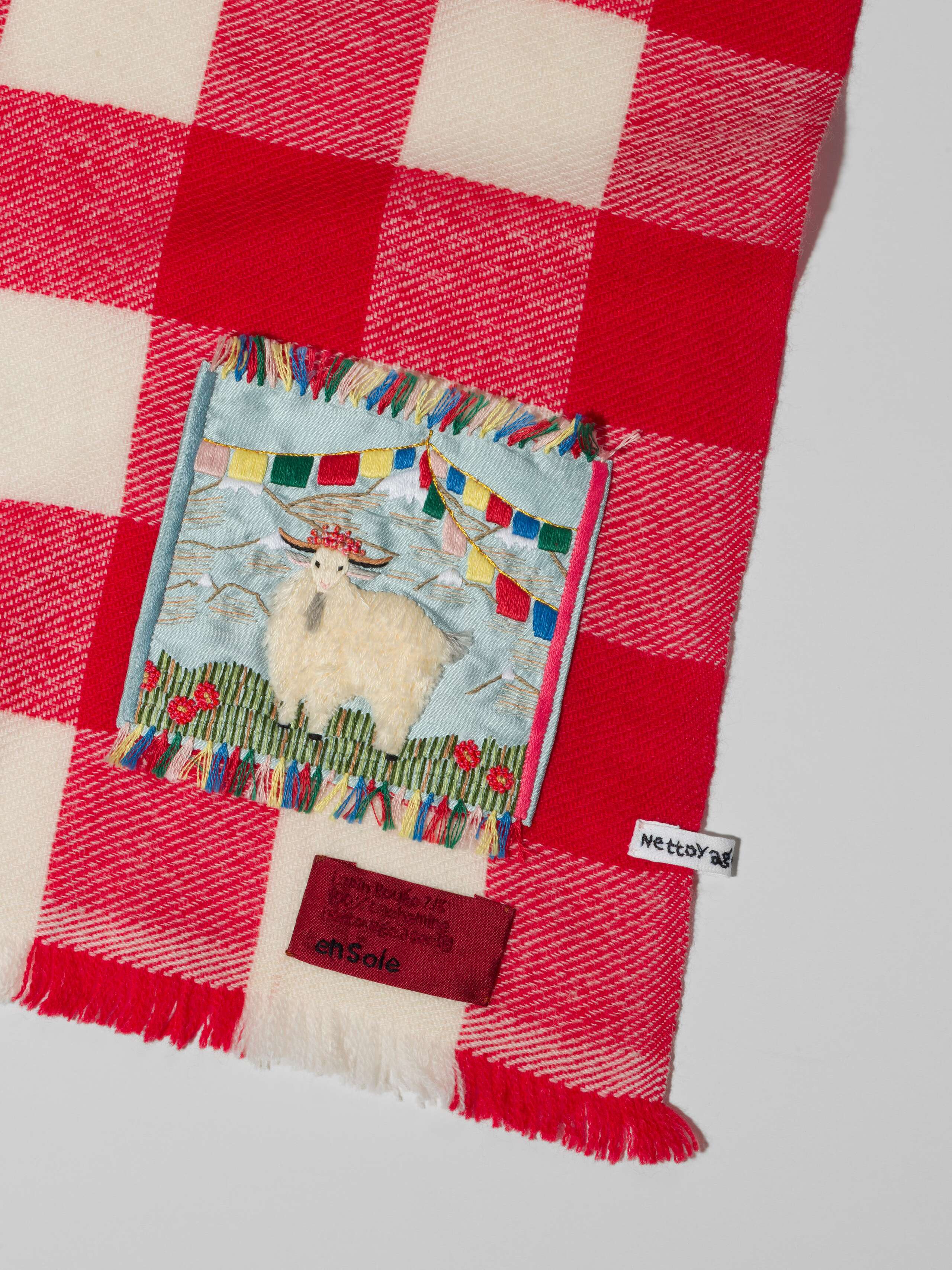 Picture of a detail of a cashmere scarf featuring a red and white check pattern