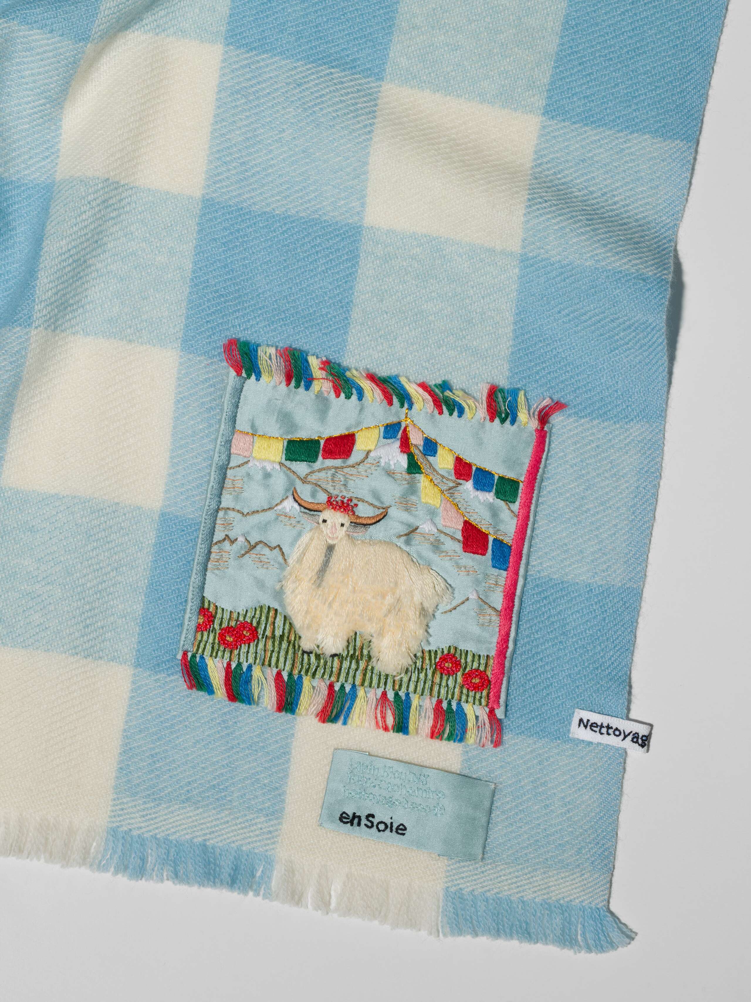 Picture of a detail of a cashmere scarf featuring a lightblue and white check pattern