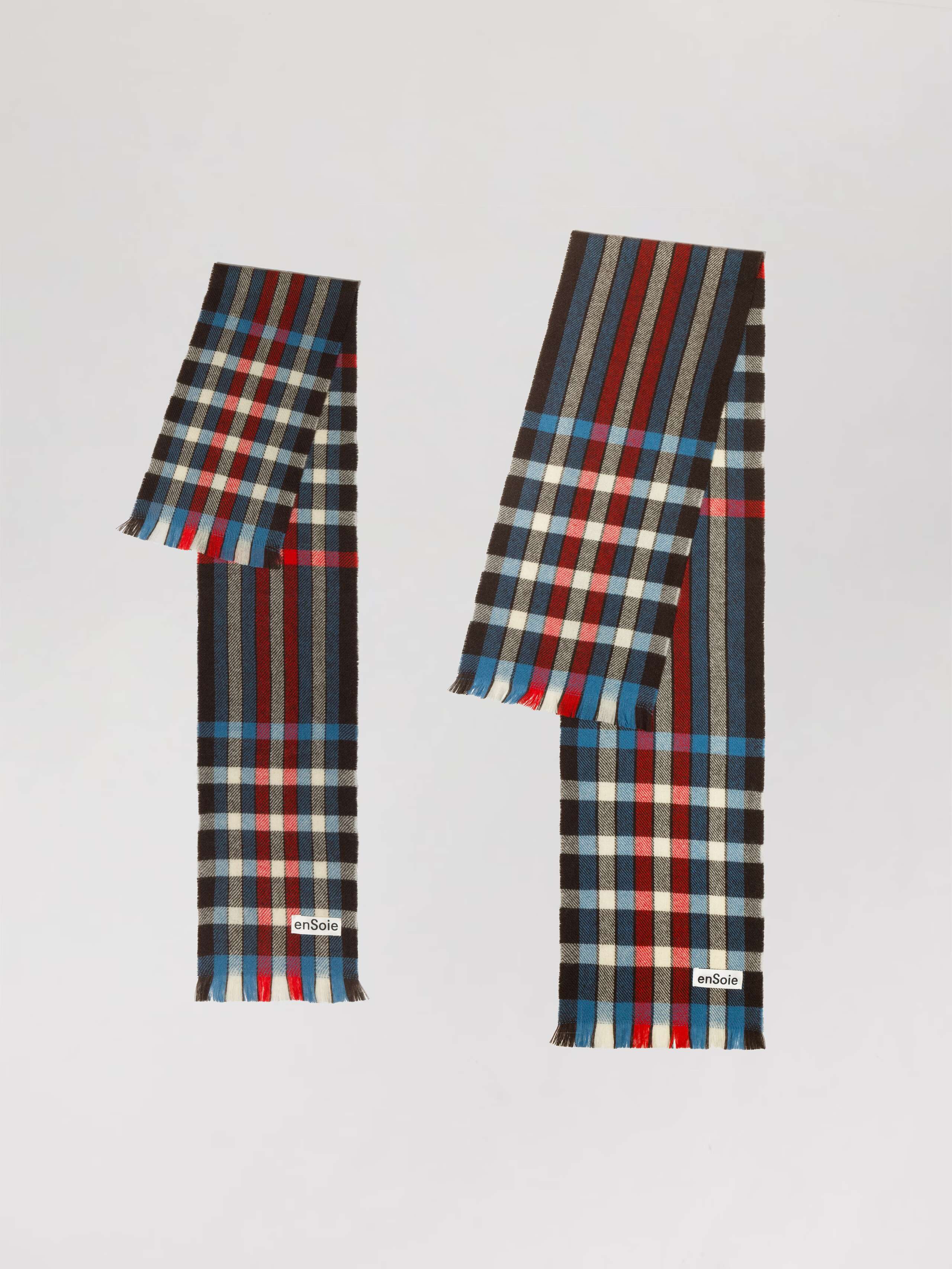 Picture of two wool scarfs featuring a check pattern in red, black, white and blue shades